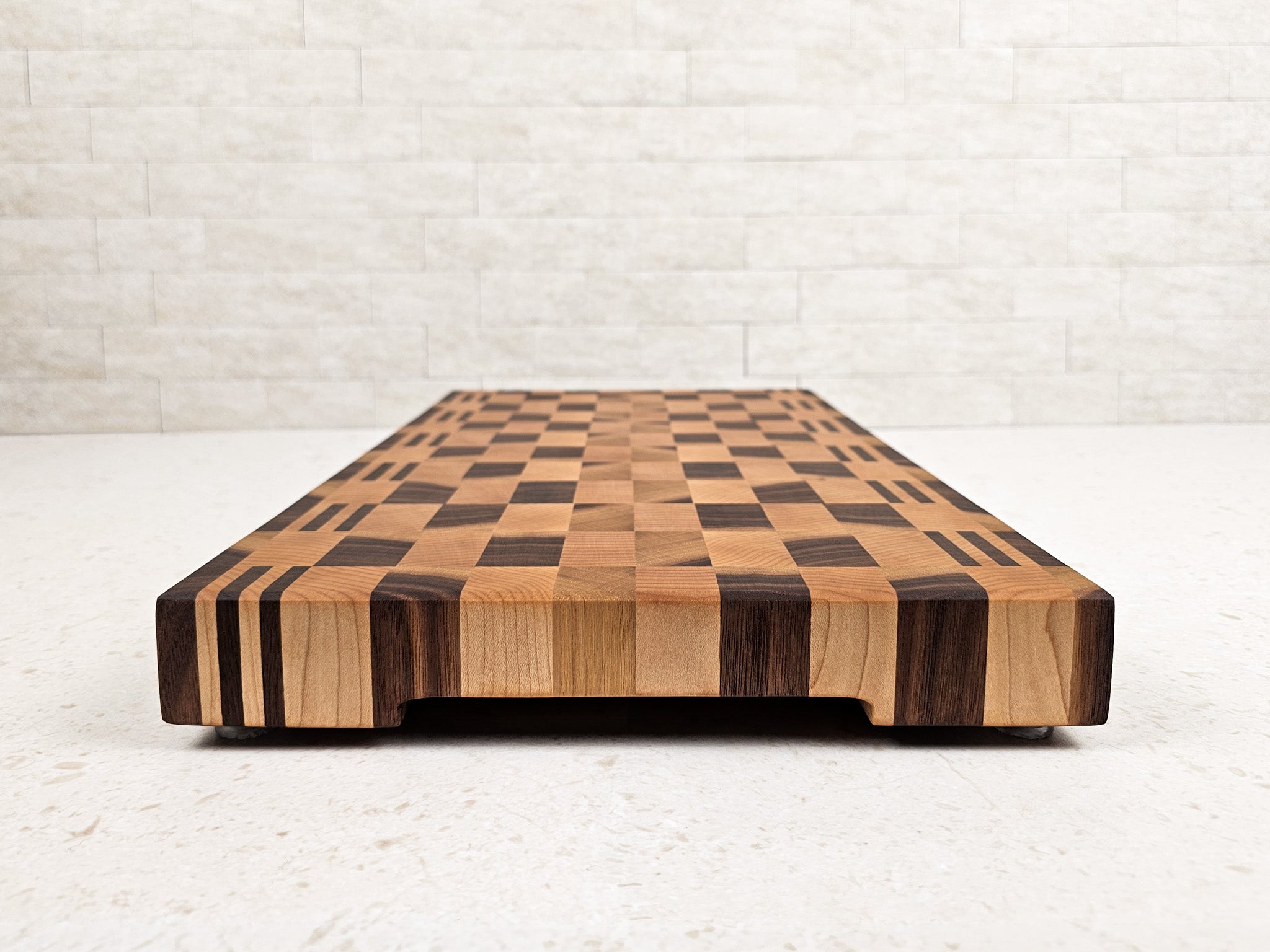 Side view of wooden cutting board showing underside finger grooves