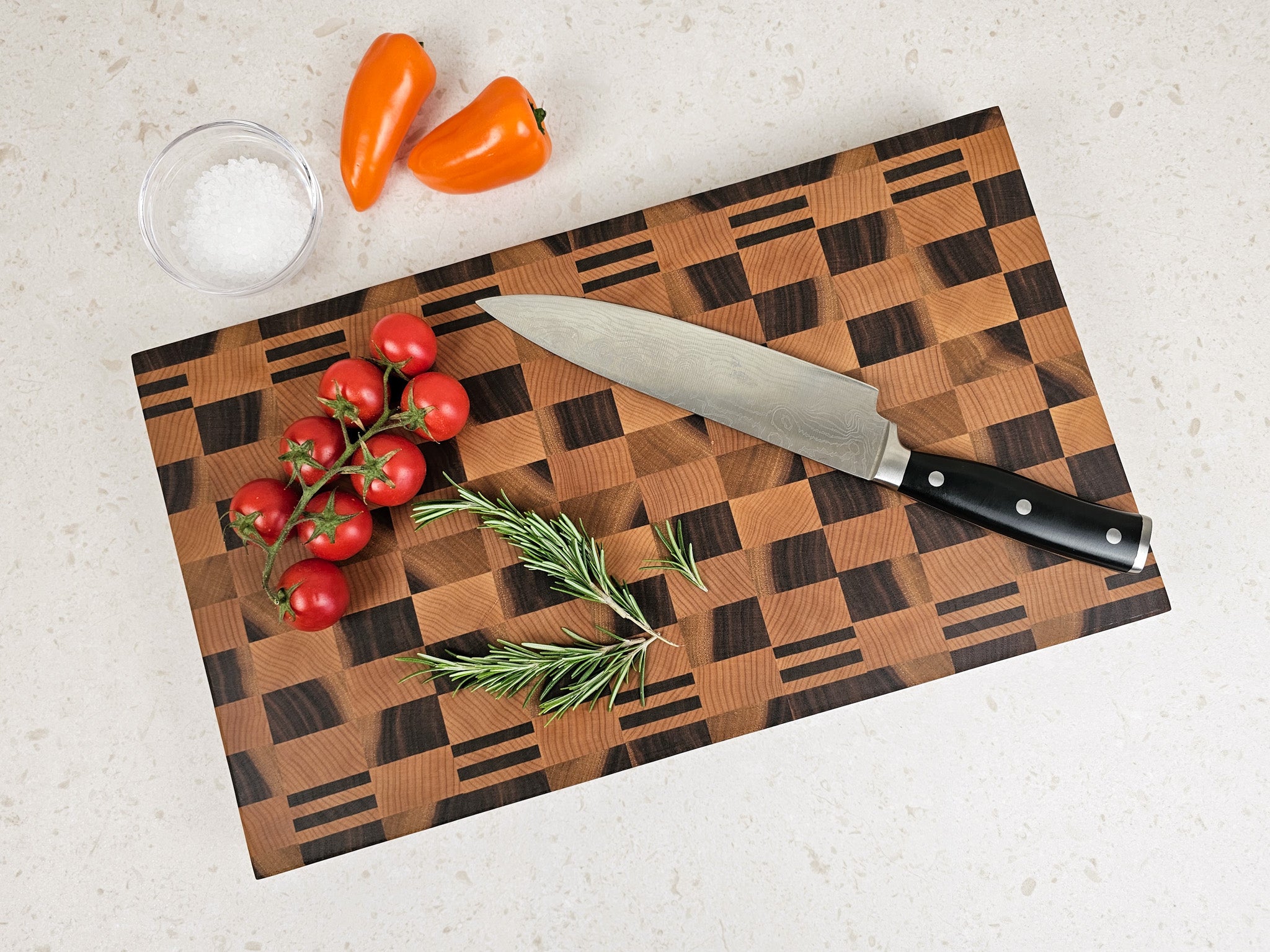 Cutting board with knife, tomatoes, and peppers on a kitchen counter