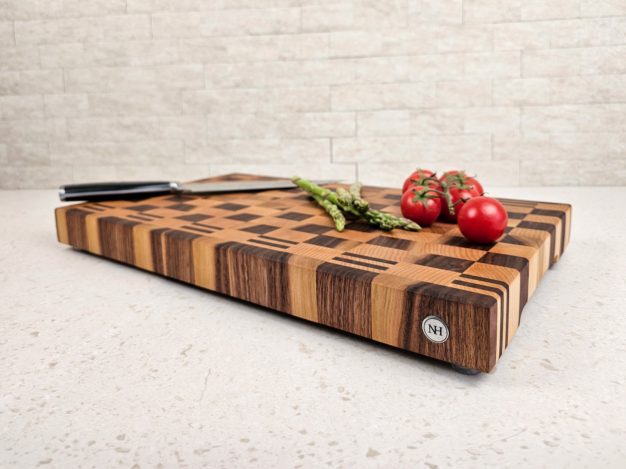 Wooden cutting board with vegetables and a knife on in a kitchen.